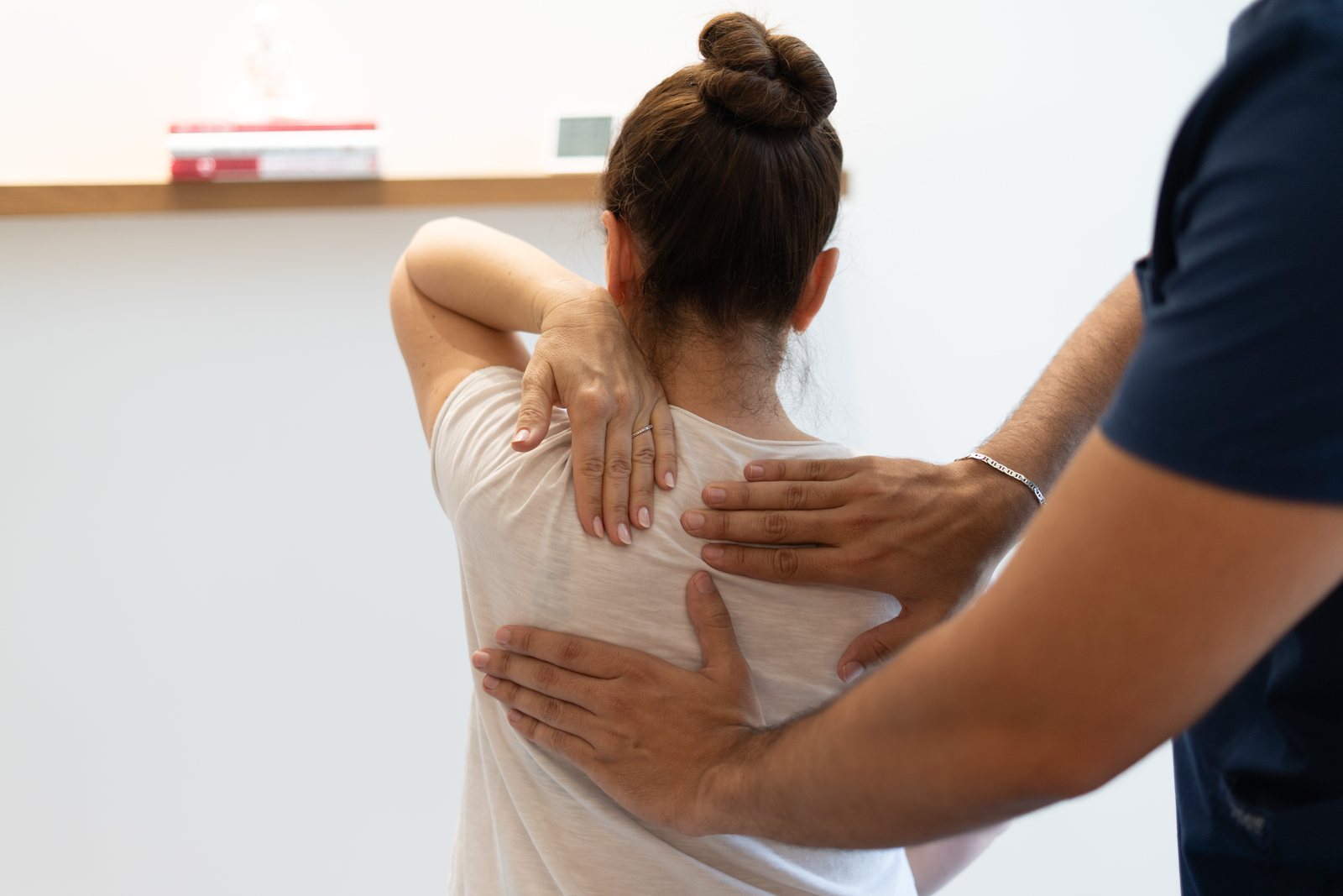 أخصائي علاج فيزيائي يعالج كتف مريضة وأعلى ظهرها في KINETIKA دبي هيلز